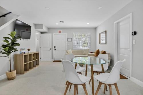 a living room with a glass table and white chairs at Sistrunk Shades Villa #4 - Townhome Downtown Fort Lauderdale Near Cruise Port & FLL in Fort Lauderdale