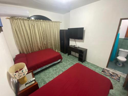 ein Wohnzimmer mit einem roten Sofa und einem TV in der Unterkunft EMMA HOUSE in Puerto Baquerizo Moreno