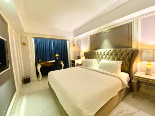 a bedroom with a large white bed and a desk at Grand Eska Hotel & Suites Batam in Nagoya