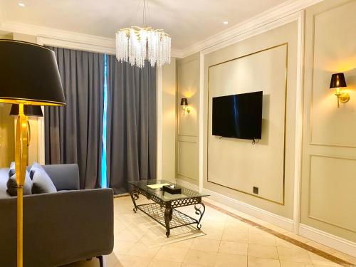 a living room with a couch and a tv on a wall at Grand Eska Hotel & Suites Batam in Nagoya