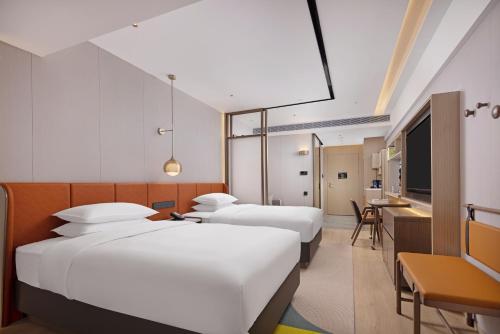 Habitación de hotel con 3 camas y escritorio. en Home2 Suites by Hilton Chengdu Kuanzhai Alley, en Chengdú