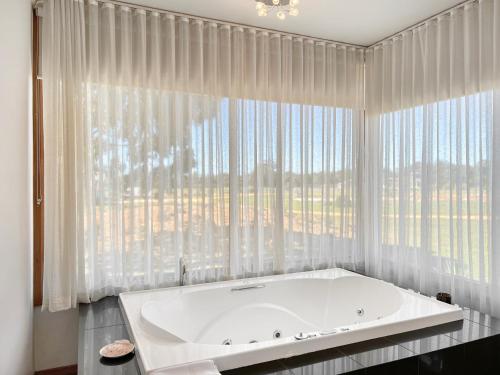 a white tub in a bathroom with a large window at Aurora Cottages Bush Retreat in Halls Gap