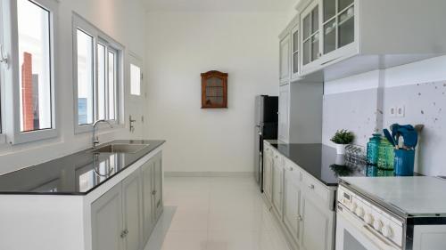 uma cozinha com armários brancos, um lavatório e janelas em The Wastoekentjana em Bandung