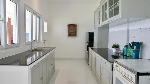 a kitchen with white cabinets and a sink and windows at The Wastoekentjana in Bandung
