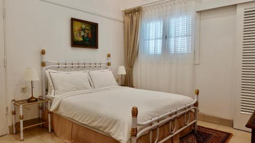um quarto com uma cama branca e uma janela em The Wastoekentjana em Bandung