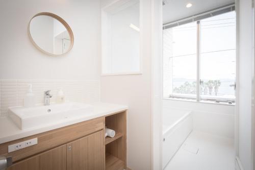 ein weißes Badezimmer mit einem Waschbecken und einem Spiegel in der Unterkunft Teshima ESPOIR PARK in Ieura