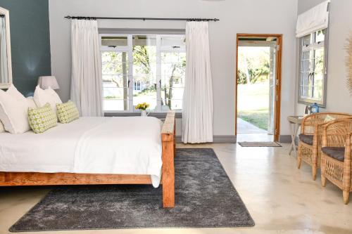 a bedroom with a large bed with white sheets at Gowan Valley Guest Farm in Balgowan