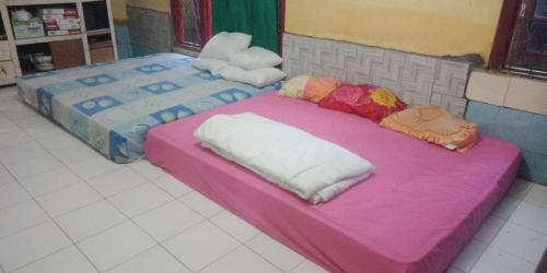 two beds in a room with a pink blanket at Agus Family Homestay in Labuan Bajo