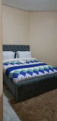 a bed with a blue and white blanket on it at Tai Homes in Eldoret