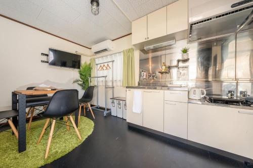 uma cozinha com armários brancos e uma mesa e cadeiras em CH Maezato em Ishigaki Island