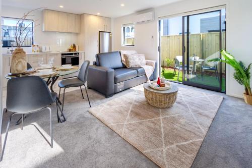 cocina y sala de estar con sofá y mesa en Coastal Sands Escape 1 bed 1 bath w/sofa bed en Christchurch