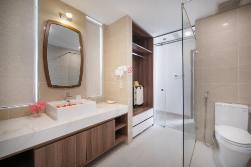 ein Badezimmer mit einem Waschbecken, einem WC und einem Spiegel in der Unterkunft RAON Hotel - STAY 24H in Quy Nhon