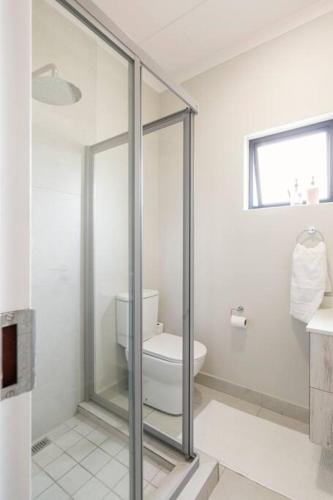 a bathroom with a toilet and a glass shower at The Blissful Abode by BK Hospitable in Midrand