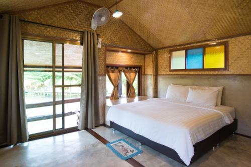 Un dormitorio con una cama grande y una ventana en เฮินไต รีสอร์ท แม่ลาน้อย, en Ban Mae La Noi