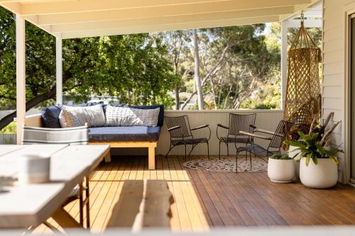 een veranda met een bank en stoelen op een terras bij The Pearl Tasmania in White Beach