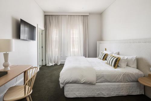 a white bedroom with a bed and a desk and a table at The Stirling Hotel in Stirling