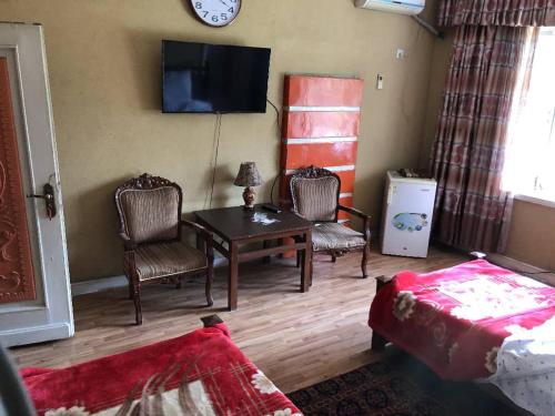 a living room with a table and chairs and a clock at Spinghar Royal Hotel in Jalalabad 