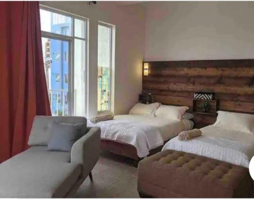 1 dormitorio con 2 camas, sofá y ventana en las palmas en Ensenada