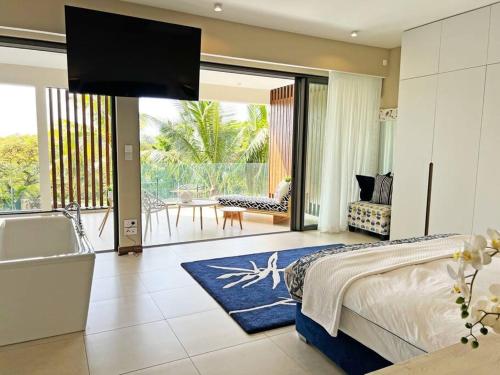 1 dormitorio con bañera, 1 cama y TV en Luxury 4 Bed Penthouse, Pool & stunning Sea views en Grand Baie