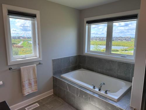 een badkamer met een bad en 2 ramen bij Guest House Ottawa - Russell in Vars