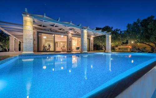 a large swimming pool in front of a house at Avra Luxury Villa & Spa in Keri