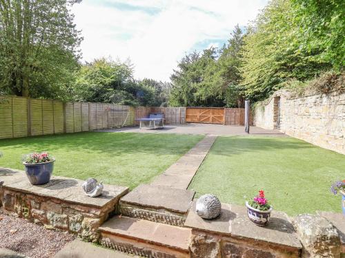 a garden with a lawn with a table and some plants at The Gatehouse in Sutton in Ashfield