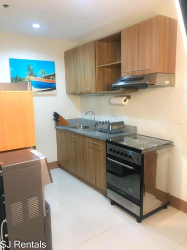 a kitchen with a black stove and a sink at 2 Bedroom Condo @ Midpoint Residences w/ City View in Mandaue City