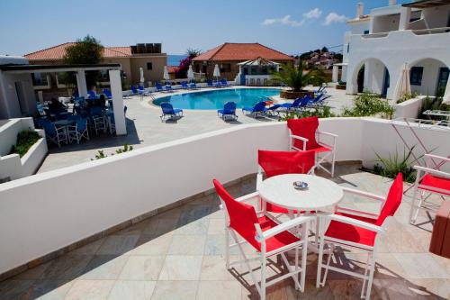 a patio with red chairs and a table next to a pool at Viva Mare Foinikounta in Finikounta