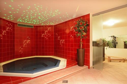 Baño de azulejos rojos con bañera y adornos navideños en Hotel Dolomites Inn, en Canazei