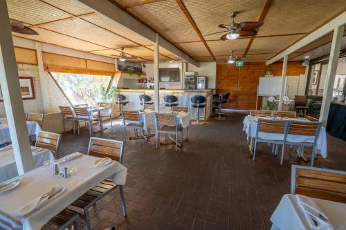 a restaurant with tables and chairs and a kitchen at Hospitality Carnarvon, SureStay Collection by Best Western in Carnarvon