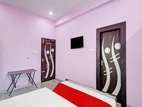 een slaapkamer met een bed en een tv aan de muur bij Urvashi Guest House in Durgapur