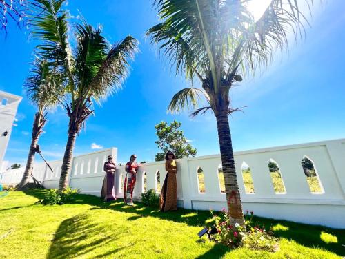 a group of people standing in front of a white building with palm trees at Amanda Villa 2 in Mui Ne