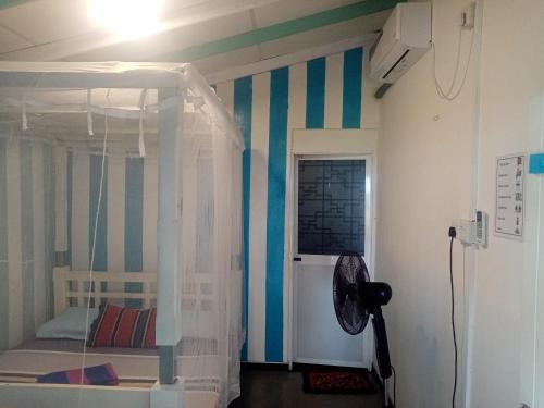 a bedroom with a bed with a striped wall at Tehan Homestay in Hiriketiya