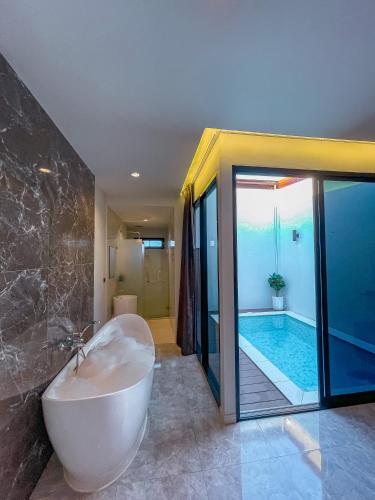 a bathroom with a tub and a swimming pool at KVILLA in Ban Khlong Bang Chak