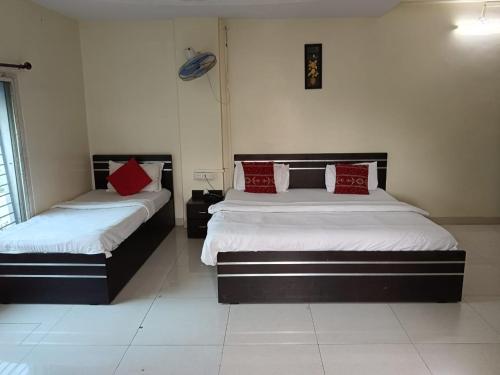 two beds in a bedroom with red pillows on them at Hotel Mahati in Indore