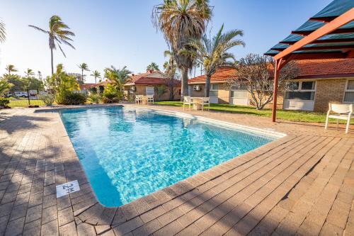 a swimming pool in front of a house at Hospitality Carnarvon, SureStay Collection by Best Western in Carnarvon