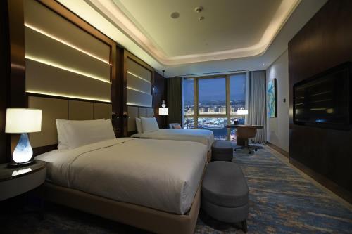 a hotel room with two beds and a television at Hilton Tashkent City in Tashkent