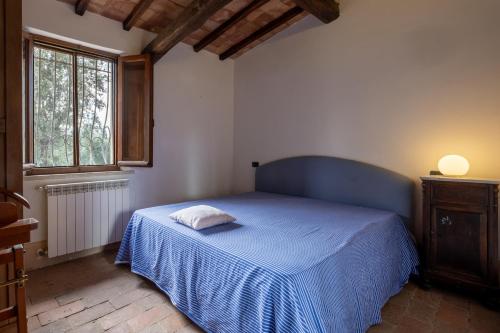 een slaapkamer met een blauw bed met een kussen erop bij Casale Pian Di Menta in Manciano