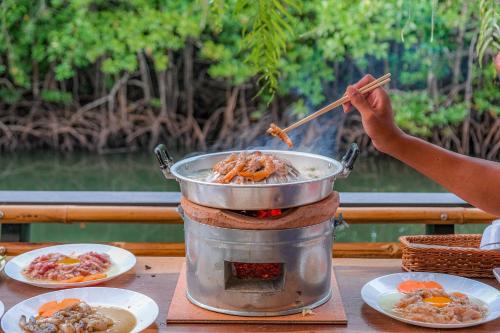 a person cooking food in a pot on a table at Escape Life Koh Kood in Ko Kood