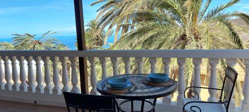 a table and chairs on a balcony with a palm tree at Vv Casa Lucas in Vallehermoso