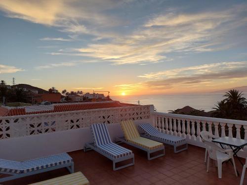 a balcony with chairs and a table and the sunset at Vv Casa Lucas in Vallehermoso