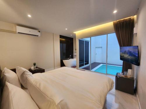 a bedroom with a large white bed and a television at KVILLA in Ban Khlong Bang Chak