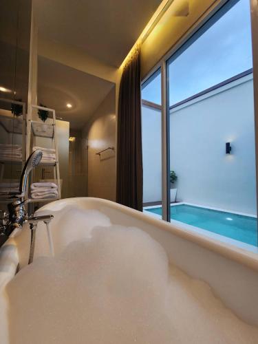 a bath tub in a bathroom with a window at KVILLA in Ban Khlong Bang Chak