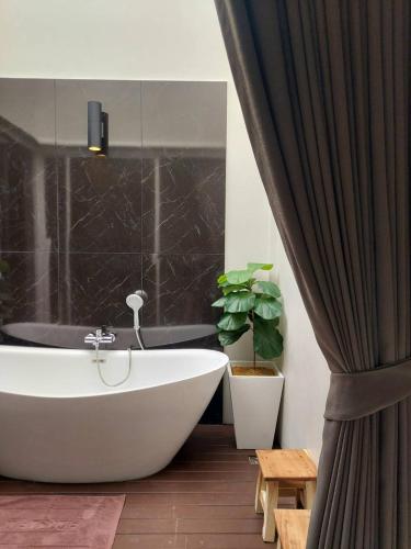 a bathroom with a white tub and a plant at KVILLA in Ban Khlong Bang Chak