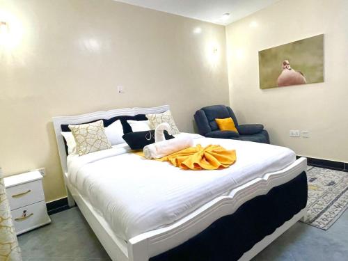 a bedroom with a large white bed and a blue chair at Xellent Suites- Marg House in Nakuru