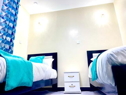 a bedroom with two twin beds with blue and white at Xellent Suites- Marg House in Nakuru