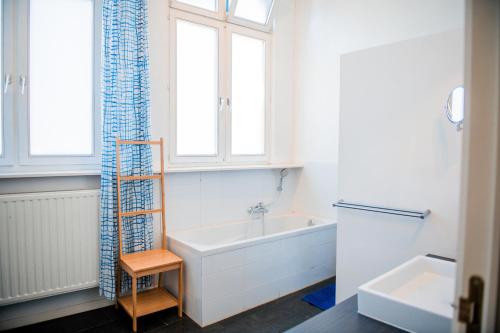een witte badkamer met een bad en een raam bij Unieke woning in het historisch stadscentrum in Antwerpen