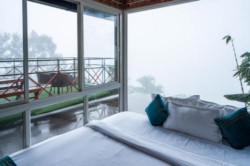 a bed in a room with a large window at Mount Stratus Resort Vayalada in Bālūssheri