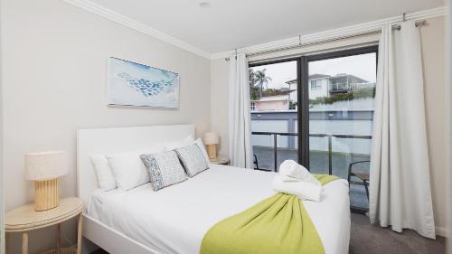 a bedroom with a white bed and a window at On the Beach Getaway in One Mile