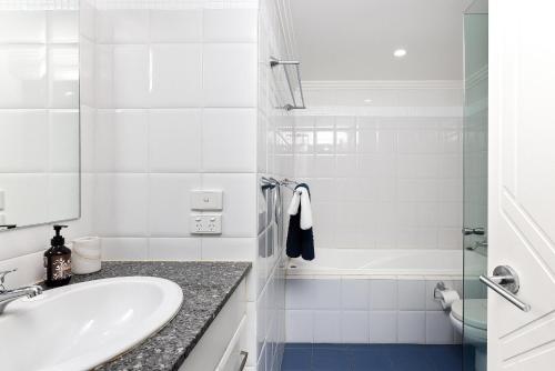 a white bathroom with a sink and a shower at On the Beach Getaway in One Mile